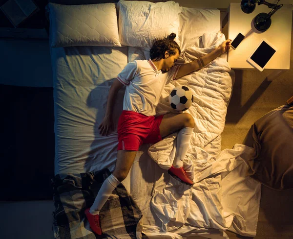 Vista superior de fútbol joven profesional, jugador de fútbol durmiendo en su dormitorio en ropa deportiva con pelota —  Fotos de Stock