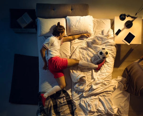 Vista superior de fútbol joven profesional, jugador de fútbol durmiendo en su dormitorio en ropa deportiva con pelota —  Fotos de Stock