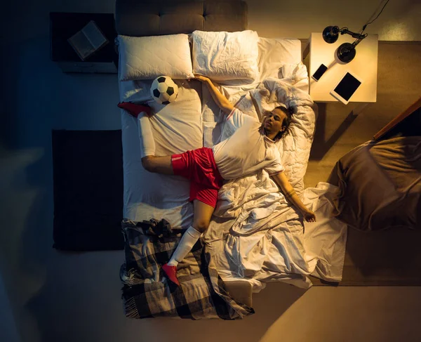 Vista superior de fútbol joven profesional, jugador de fútbol durmiendo en su dormitorio en ropa deportiva con pelota —  Fotos de Stock