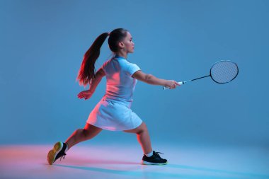 Badminton 'da pratik yapan güzel cüce kadın mavi arka planda neon ışıkta izole edilmiş.