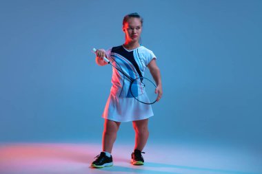 Badminton 'da pratik yapan güzel cüce kadın mavi arka planda neon ışıkta izole edilmiş.
