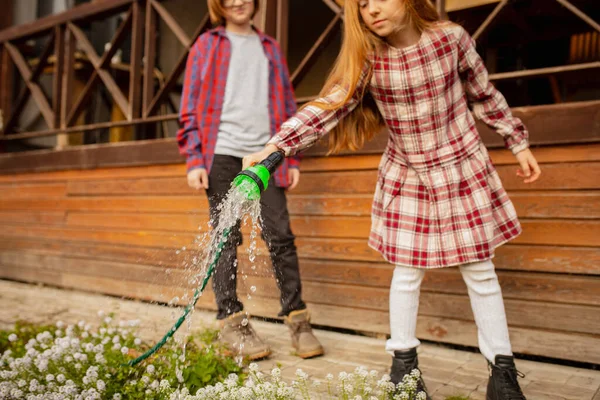 Gelukkig broer en zus water geven planten in een tuin buiten samen — Stockfoto