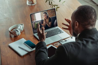 Evden çalışan bir adam, uzak ofis konsepti. Dizüstü bilgisayarla iş yapan genç işadamı, müdürün online konferansı var.