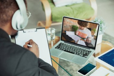 Evden çalışan bir adam, uzak ofis konsepti. Dizüstü bilgisayarla iş yapan genç işadamı, müdürün online konferansı var.