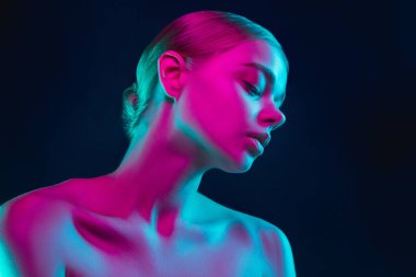 Karanlık stüdyo arka planında neon ışıklı kadın model portresi.