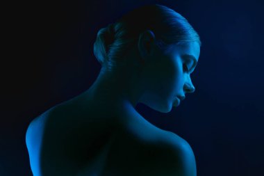Karanlık stüdyo arka planında neon ışıklı kadın model portresi.