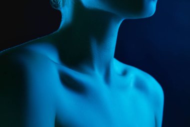Karanlık stüdyo arka planında neon ışıklı kadın model portresi.