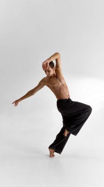 Hareketli etkileyici erkek dansçı çıplak gövde ve duygusal odaklanma ile poz veriyor. Performans sanatı, vücut araştırmaları, duygusal farkındalık ve modern erkeklik hassasiyeti kavramı.