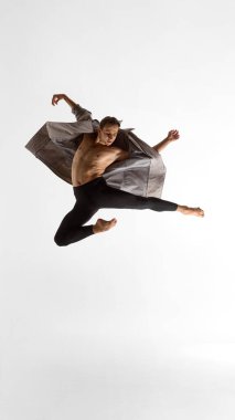 Erkek dansçı, dinamik bir ifadeyle ve korkusuz bir duygusal güçle açık ceketle zıplıyor. Yayın erkek giyim, performans sanatı, müzik görselleri ve vücut anlatımı kavramı.