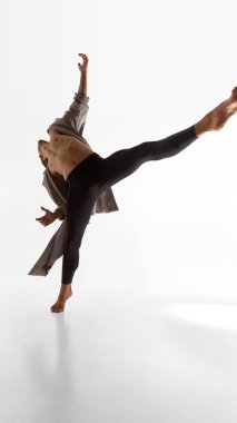 Erkek dansçı, göğsü açık ve duygusal özgürlüğe sahip ceketiyle vücudunu yana doğru uzatıyor. Performans sanatı, vücut araştırmaları, farkındalık ve müzik görselleri kavramı.