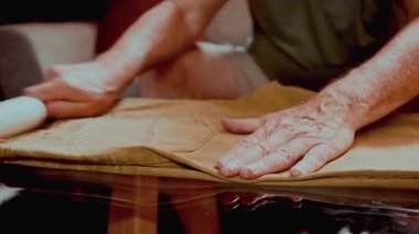 Giysi bakımı için katlanmış pantolona pamuk sarma kullanan yüzü olmayan adam. Ev bakımı, moda detayı, düzenlilik, yaşam tarzı rutini ve düzenli alışkanlıklar kavramı.