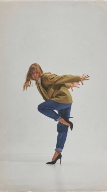 Spor ceketli kadın, dinamik artistik hareketlerle, kot ve topuklu ayakkabılarla poz veriyor. Güçlendirme, yaratıcılık, moda zarafeti, yaşam tarzı ve markalaşma tasarımı kavramı.