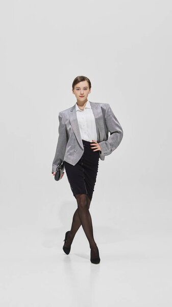 Confident woman in silver blazer walking with clutch and bold expression. Concept of ambition, corporate lifestyle, career drive, independence, and empowerment.