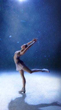 Düşen kar ışığı altında kollarını uzatarak dinamik poz veren artistik patinajcı. Hareket enerjisi, zindelik gücü, moda zarafeti, editörlük sanatı, ruhsal özgürlük kavramı.