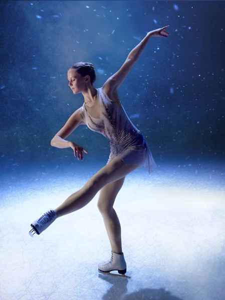 Zarif artistik patinajcı. Kolunu ve bacağını poz vererek uzatıyor. Yaşam tarzı, sağlık dengesi, kültürel sanat ve editoryal zarafet kavramı.