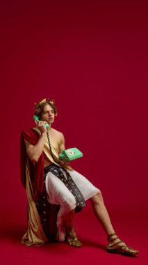 Toga giymiş genç bir adam eski yeşil telefon namlusunda oturuyor. Sosyal medya mizah anlayışı, dönem karşılaştırması, yaşam tarzı dergileri ve yaratıcı reklam kampanyaları kavramı.