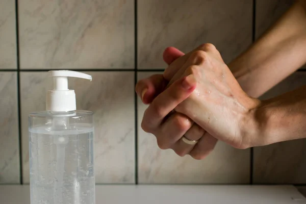 Woman using hand sanitizer on hands. The action of rubbing hand sanitizer on both hands.