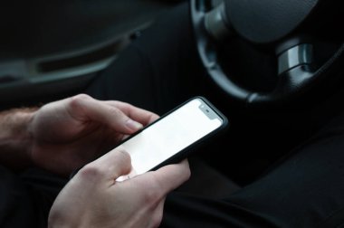 Beyaz ekranlı akıllı telefon direksiyondaki erkek eli, yaşam tarzı, sade anahtar.