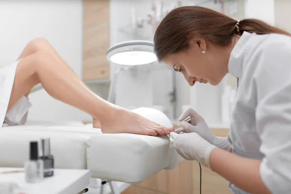 Podólogo pintando unhas e fazendo procedimento para o pé . — Fotografia de Stock