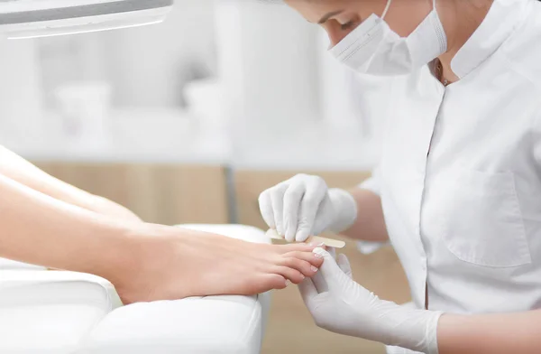 Nail artist in beauty salon polish nails on foot by tool. — Stock Photo, Image