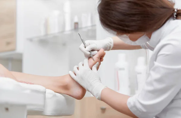 Doctor haciendo procedimiento de limpieza cliente pie con herramienta de hierro especial . — Foto de Stock