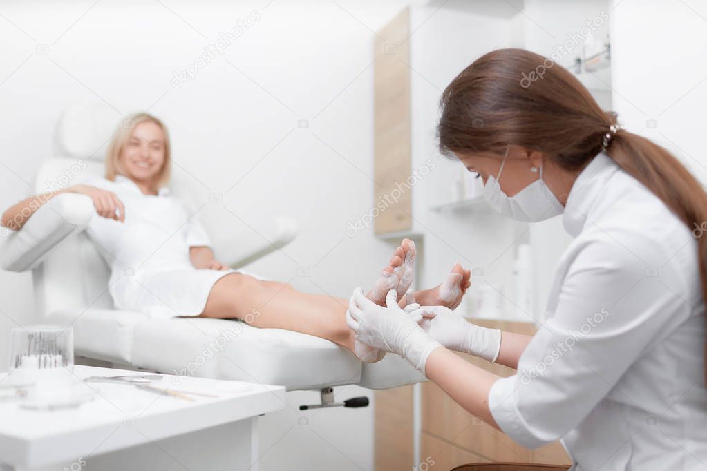 Podiatrist female doctor making procedure of massage and peeling.