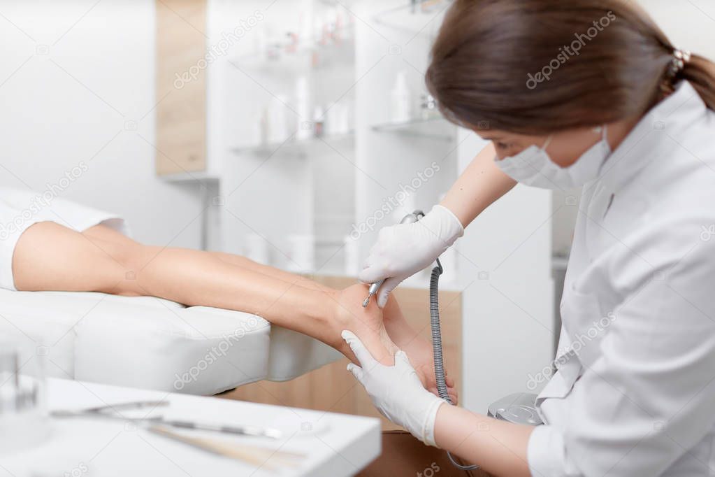 Woman relaxing at beauty salon, when podiatrist making procedure for feet.