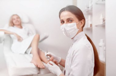 Podiatrist in mask on face looking at camera and working. clipart