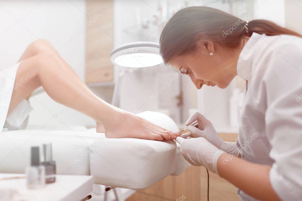 Podiatrist painting nails and making procedure for foot.
