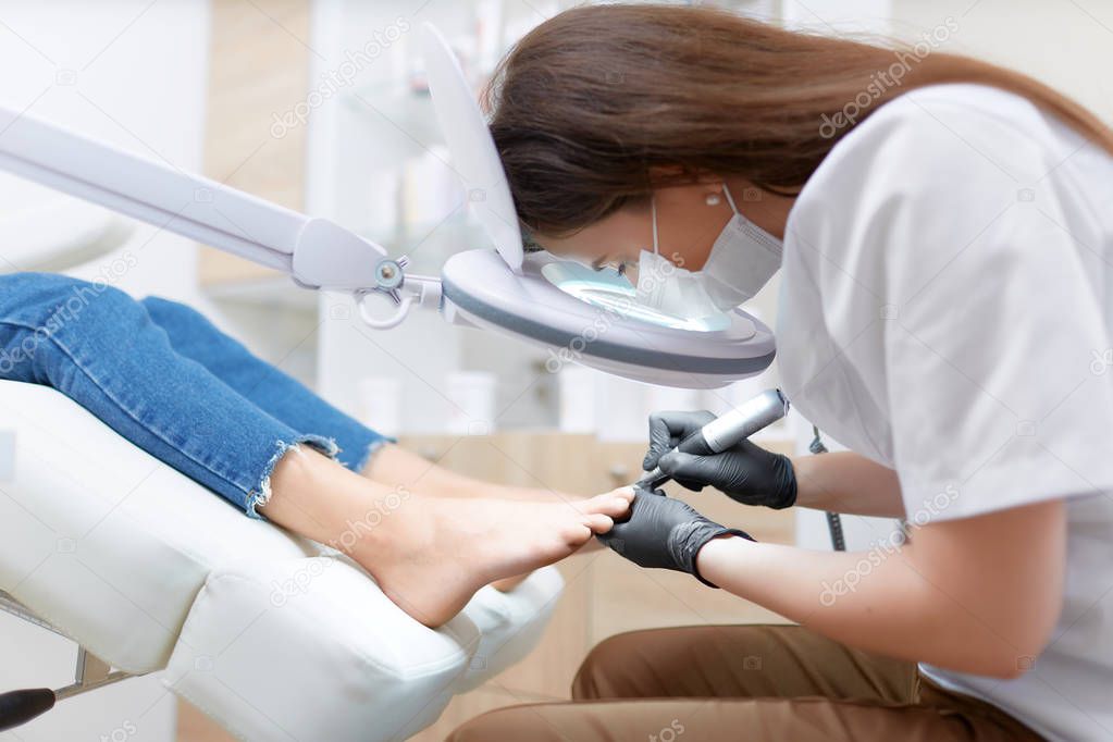 Podiatrist doctor in white making polish procedure for foot.