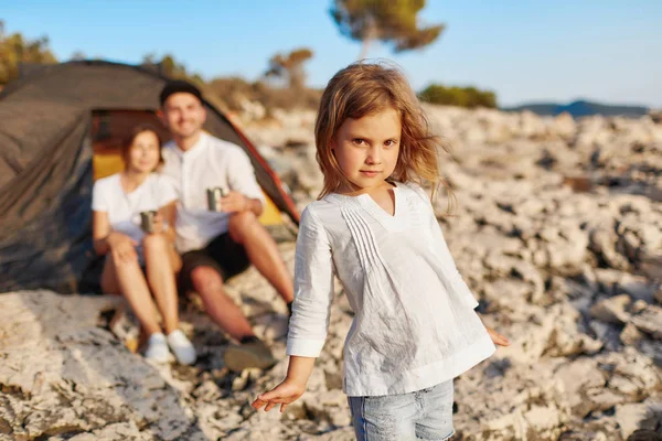 Meisje met bruine ogen, permanent op rotsachtige strand en camera te kijken. — Stockfoto