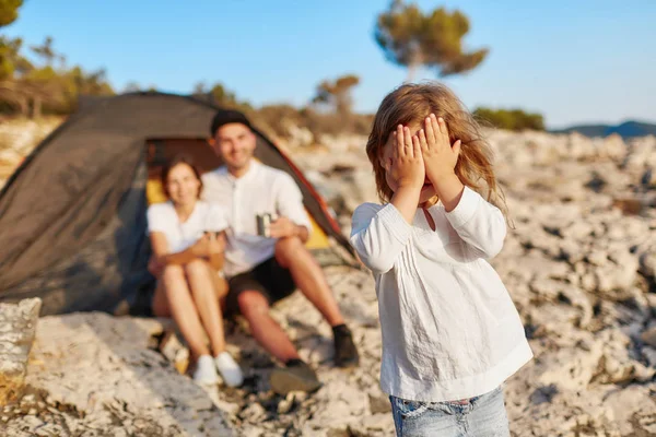 Mooi meisje permanent op rotsachtige strand en ogen die betrekking hebben op gezicht met de hand sluiten. — Stockfoto