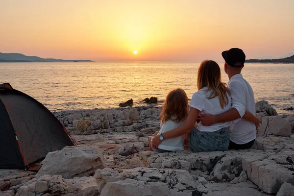 Achteraanzicht van vriendelijke familie bewonderen van de ondergaande zon over zee. — Stockfoto