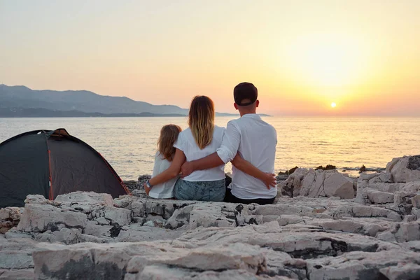 Achteraanzicht van vriendelijke familie bewonderen van de ondergaande zon over zee. — Stockfoto