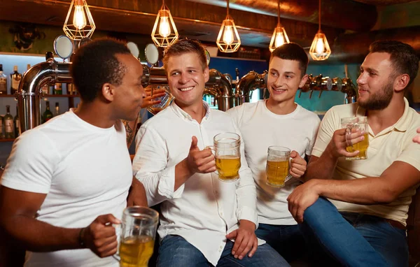 Company of four cheerful men enjoying light beer in stylish pub. — Stock Image Company of four cheerful men enjoying light beer in stylish pub. Royalty Free Stock Photos