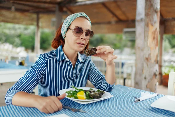 Junge Frau isst Auster in einem Restaurant im Freien — Stockfoto