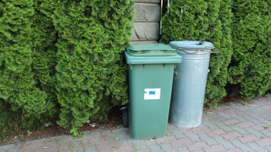 Özel bir evin bahçesindeki çitin yanında iki plastik sepet. Ayrı atık ayıklama. Çevreye karşı sorumlu tutum. Sıfır atık.