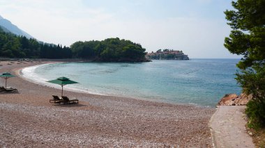 Boş plaj, güneşli şezlonglar, plaj şemsiyeleri. Sakin deniz, güzel bulutlu gökyüzü. Gezginlerin ve turistlerin olmadığı bir sahil..
