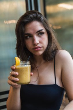 Güler yüzlü lezzetli tatma ve uzak kafede dinlenirken bakarak gündelik kıyafeti genç ve güzel esmer