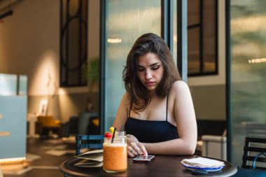 Güler yüzlü yakınındaki kafede masada güzel genç esmer oturma ve modern smartphone tarama