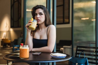 Güzel yüzlü içme ve uzakta şık kafe masada otururken arıyorum güzel genç bayan