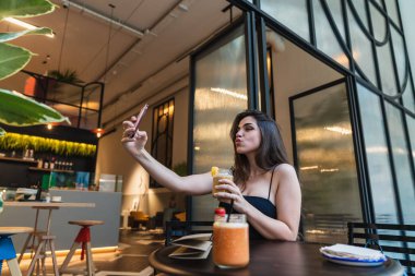 Taze yüzlü bardak tutan ve hava kafe masada otururken öpüşme genç ve güzel esmer 