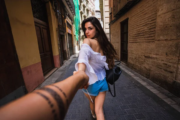 Arkadan görünüşü tanınmaz halde kişinin elini tutarak ve Valencia İspanya dar sokakta yürürken rahat kıyafet içinde oldukça genç bayan