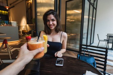 Gülümseyen ve şık kafe ve prangalara bardak taze yüzlü tanınmaz arkadaşıyla otururken kameraya bakarak güzel genç kadın