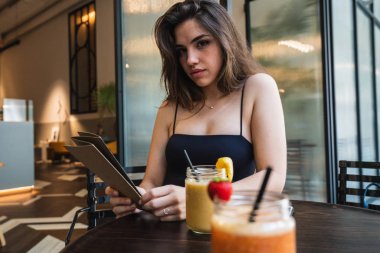 Menü tutarak ve güler yüzlü bardak yakınındaki güzel kafede masada otururken kameraya bakarak çekici genç hanım