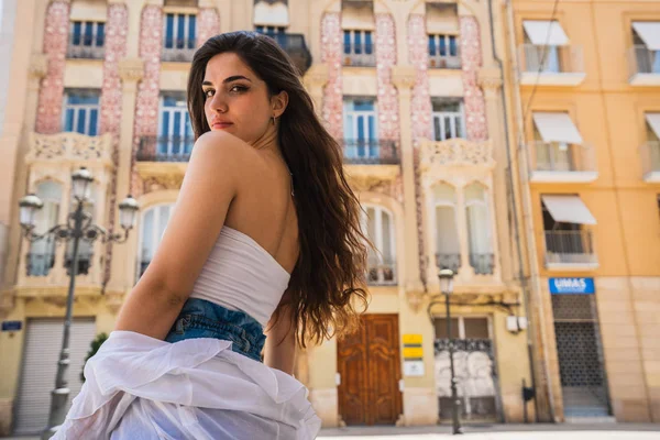 Güzel bayanı rahat kıyafet kamera güzel binaları Valencia arka plan üzerinde dururken bakarak yan görünüm
