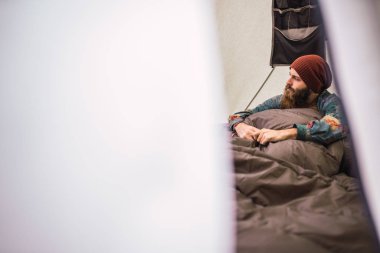 Şapka uzakta çadır Monument Valley, Utah içinde sıcak battaniye altında otururken arıyor çekici sakallı erkek