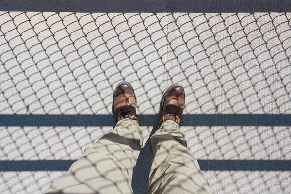 上記の作物は茶色の靴 グランドキャニオン アリゾナ州の鉄柵の影を道路に立っている男性の足 — ストック写真
