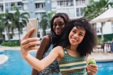 Havuz üzerinde yakın duran ve selfie smartphone ile mutlu bir şekilde alarak kadınlar Genç siyah