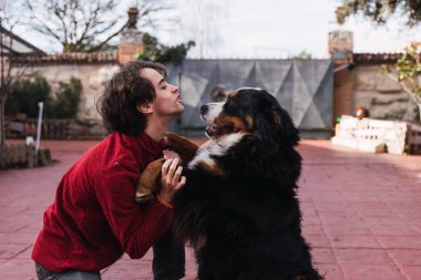 Kucaklayan ve pençeleri Bernese dağ köpek sokakta oturan tutan adam yan görünüm
